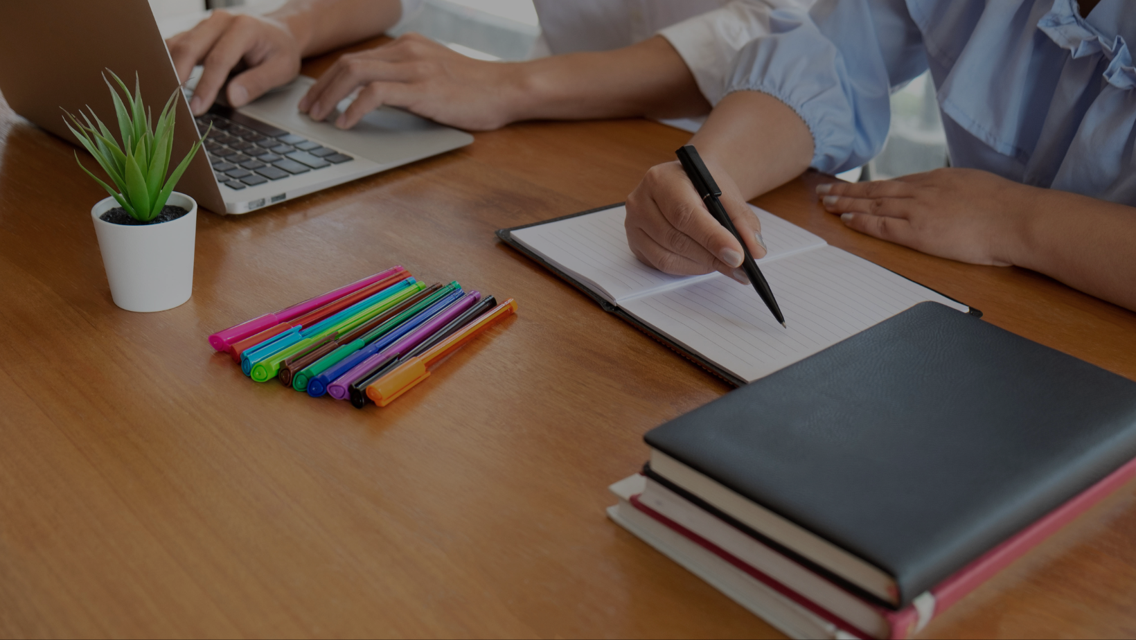 A person is writing in a notebook at a table. There is a laptop, books, and colored pens on the table. The text "Summer Refresh: Top Books & Podcasts For Teachers & Tutors" is superimposed over the image.