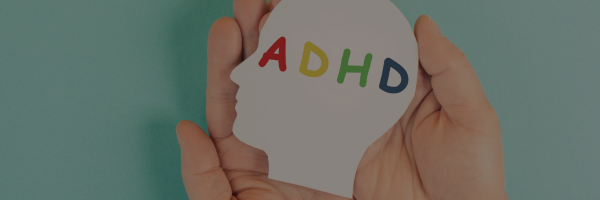 A pair of hands cradling a paper cutout of a head with the letters A, D, H, and D in different colors.