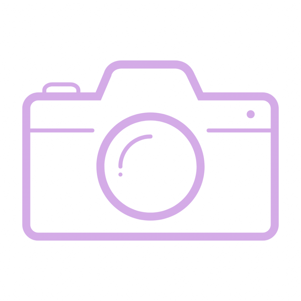 A minimalist outline icon of a digital camera in light purple. The camera features a large circular lens, a small viewfinder on the left, and a dot on the right, possibly indicating a flash or sensor.