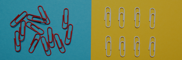 A pile of red paper clips scattered on a blue background on the left side, and two neat rows of white paper clips arranged evenly on a yellow background on the right side, illustrating contrast between disorder and organization.