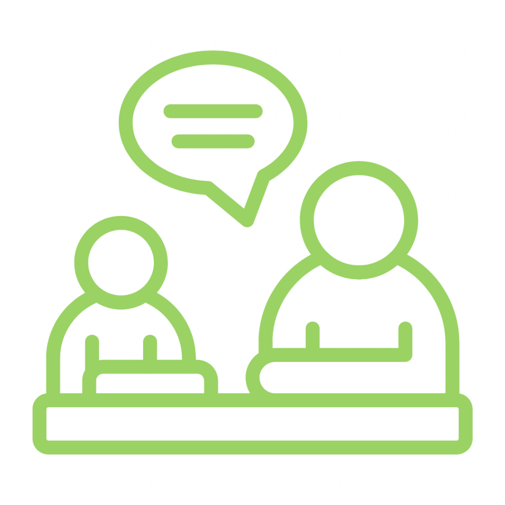 Green line drawing of two people seated at a desk or counter, with a speech bubble above them, representing a conversation, interview, or consultation.